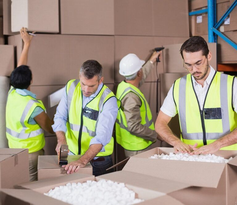 Warehouse workers in yellow vests preparing a shipment