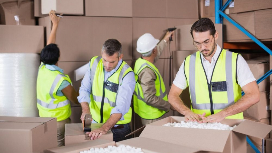 Warehouse workers in yellow vests preparing a shipment