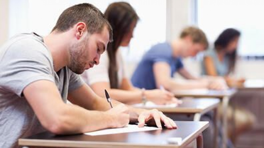 handsome student writing an assignment in a classroom