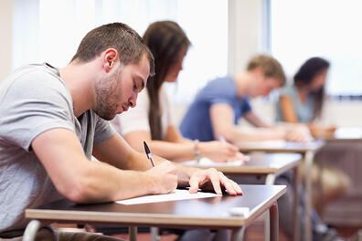 handsome student writing an assignment in a classroom