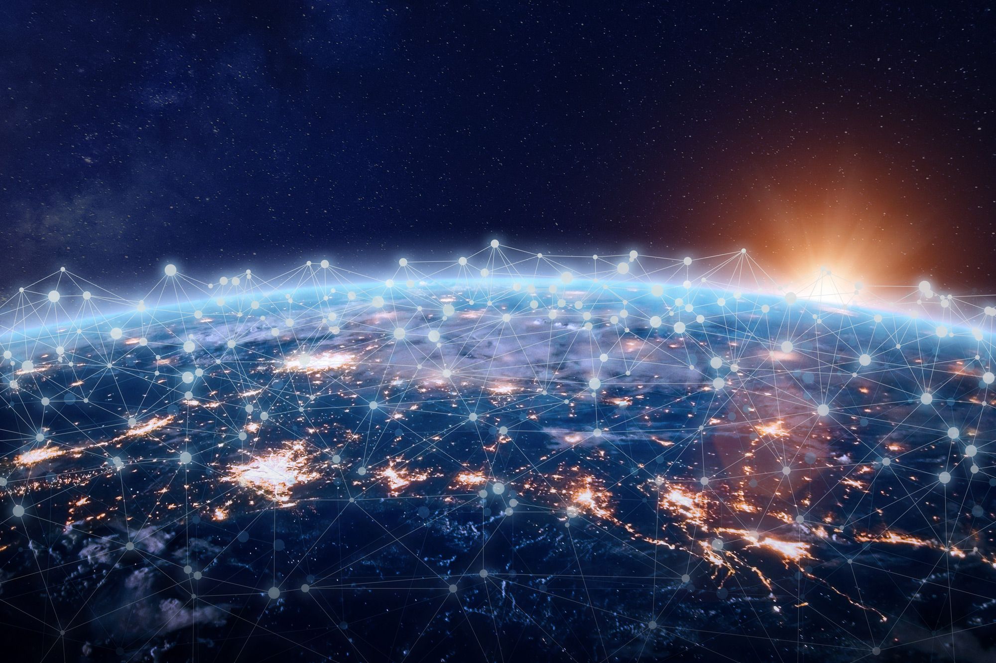 View of Earth from space at sunrise, showing bright city lights and a network of connected points and lines across the surface, symbolizing global communication and connectivity.