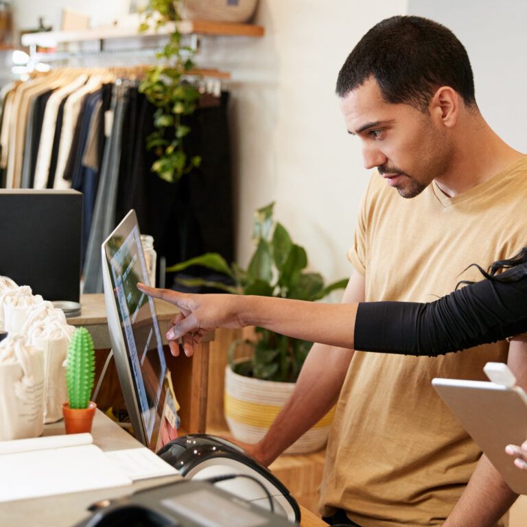 A retail management systems consultant helps an employee learn a new retail management software.