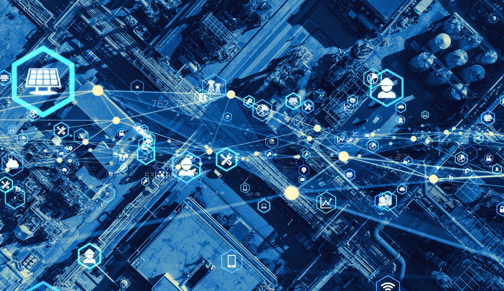 Aerial view of an industrial site overlaid with digital icons and lines representing data, connectivity, and supply chain optimization. The blue tint signifies a modern, connected industrial environment.
