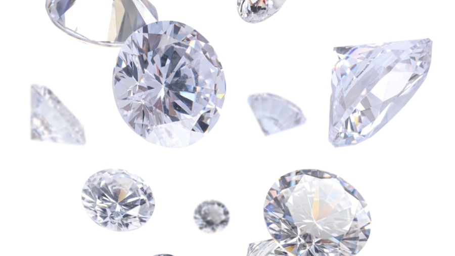 Several sparkling, faceted diamonds of various sizes appear to be floating or falling against a white background, shimmering with elegance beyond any tariff.
