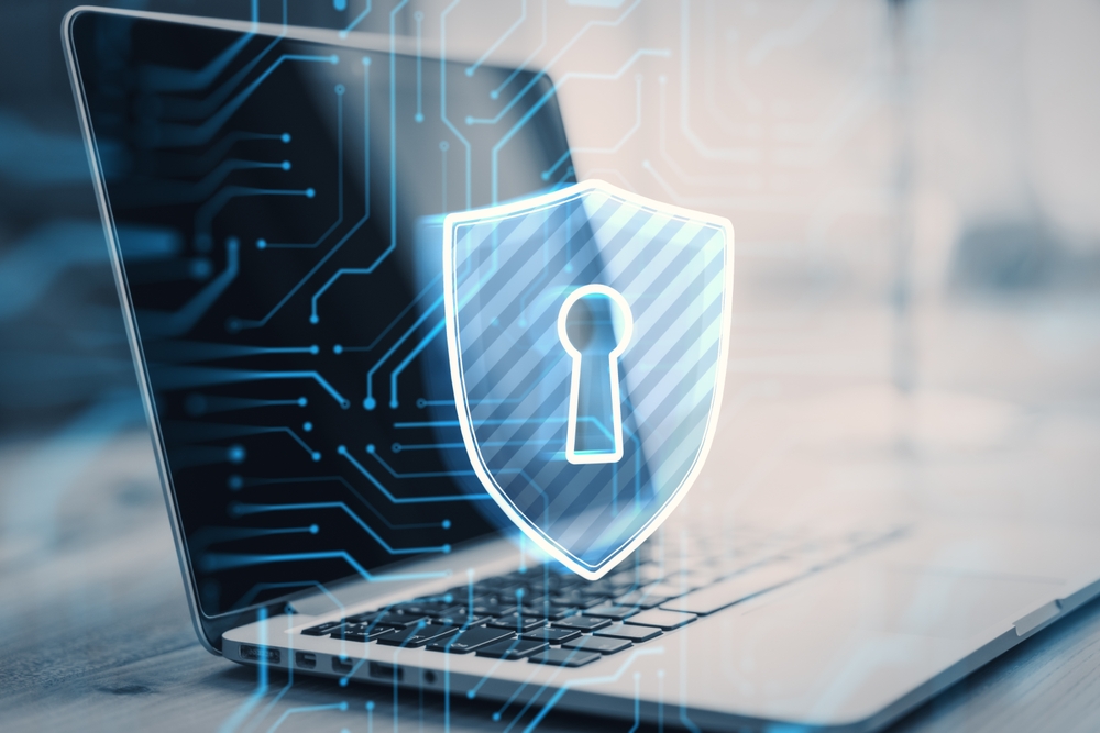 A laptop with a digital shield and keyhole icon overlay, symbolizing cybersecurity and data protection, set against a background of circuit patterns.