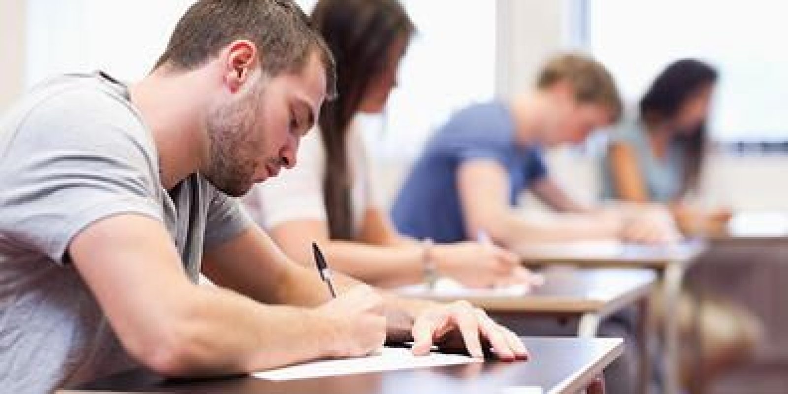 handsome student writing an assignment in a classroom
