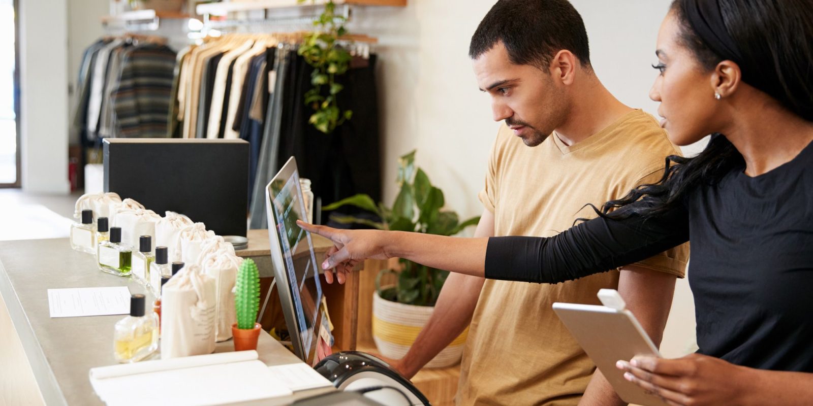 A retail management systems consultant helps an employee learn a new retail management software.