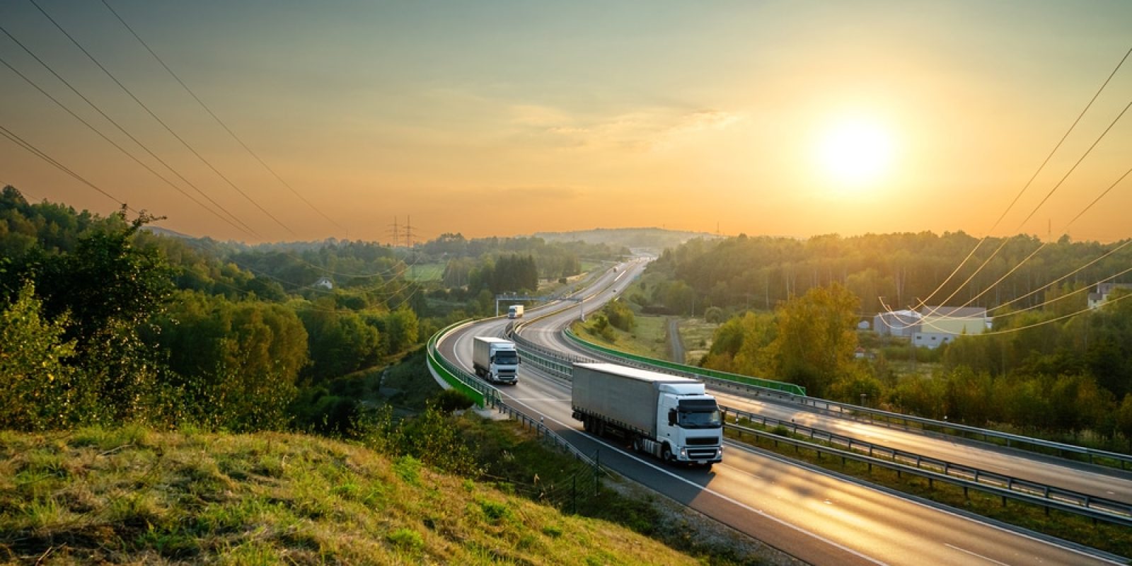 White,Trucks,Driving,On,The,Highway,Winding,Through,Forested,Landscape