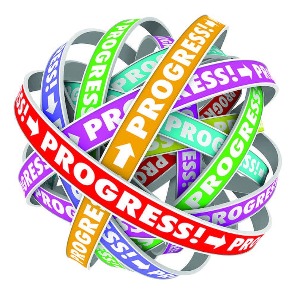 A tangled ball of colorful ribbons with the word “PROGRESS!” and arrows printed on each in various colors, symbolizing movement, advancement, and complexity.