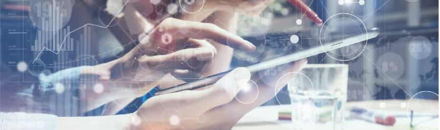 Close-up of people’s hands using a tablet, with one pointing at the screen and another holding a stylus. Overlay of digital data graphics suggests a technology or business setting.