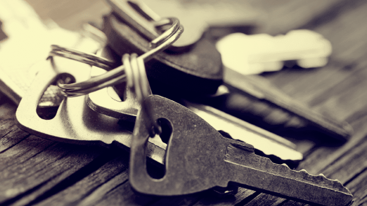A close-up of several metal keys on a keyring resting on a wooden surface, with a soft focus and warm lighting.