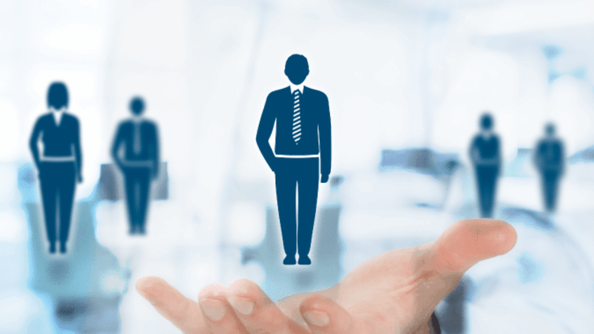 A person holds out their hand with illustrated icons of business professionals, symbolizing talent selection or human resources, against a blurred office background.