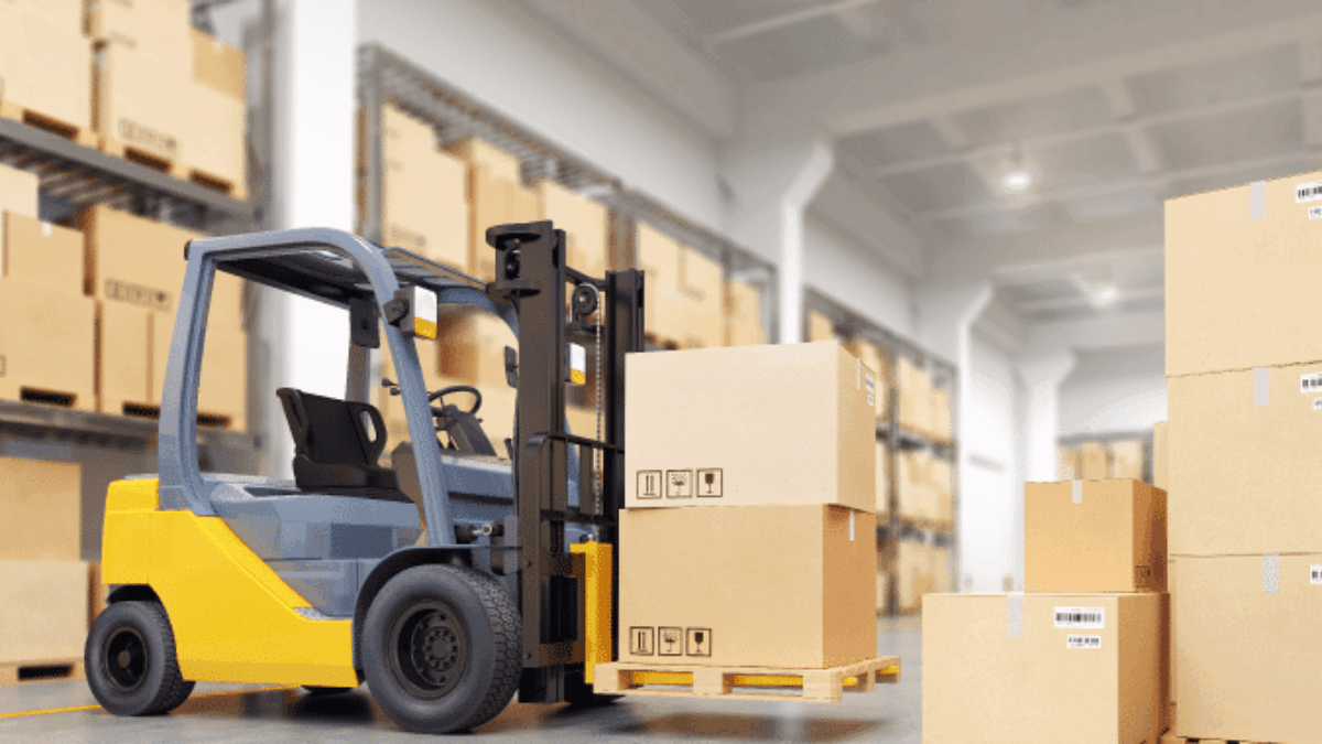 A yellow forklift moves a pallet with cardboard boxes inside a warehouse with shelves stacked with similar boxes.