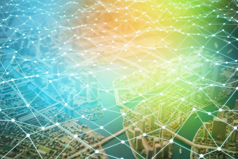 Network Strategy-385934-edited A digital illustration of a city landscape overlaid with a glowing network of interconnected lines and dots, symbolizing connectivity or smart city technology in the retail supply chain, set against a gradient blue to yellow background.