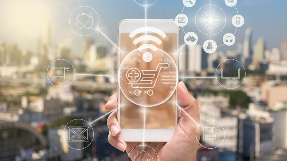 A hand holds a smartphone against a blurred cityscape, displaying a digital shopping cart icon. Translucent icons for order management systems and online services float around the phone, highlighting seamless connectivity.