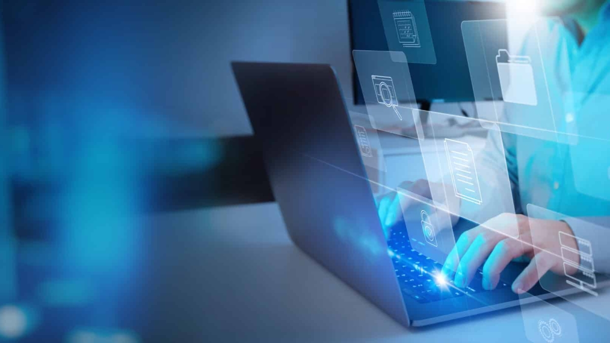 A person types on a laptop with digital icons for cloud storage, folders, and data projected in the air, representing technology and digital file management.