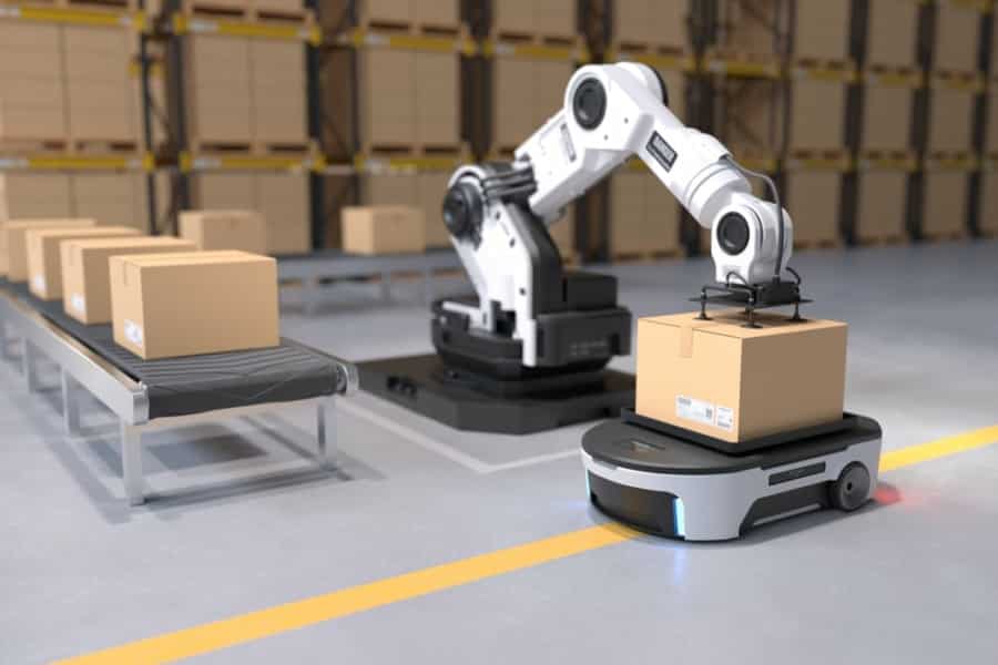 image – 2025-04-09T163708.216 A robotic arm places a cardboard box onto a mobile robot in a warehouse, offering a glimpse into the future of supply chain, with shelves of boxes in the background and a conveyor belt carrying more boxes on the left side.