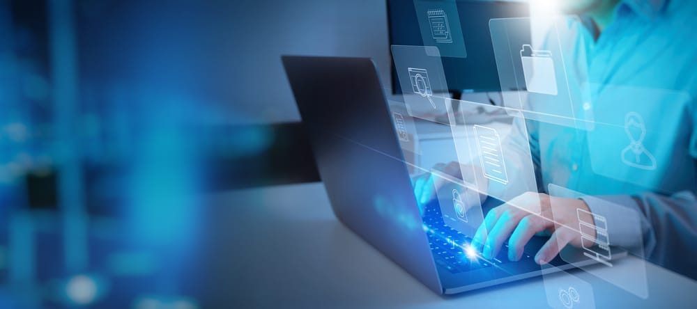 Person typing on a laptop with holographic icons for files, folders, and data storage, symbolizing digital data management and the comparison of business central vs finance and supply chain management in information technology.