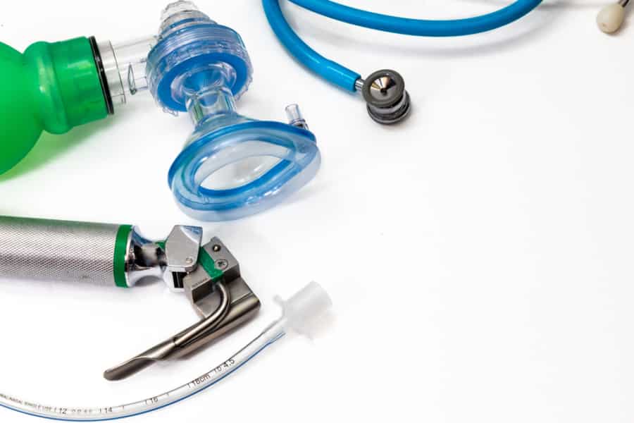A close-up of medical equipment, including a green manual resuscitator, blue oxygen mask, laryngoscope, endotracheal tube, and stethoscope on a white background—ideal for illustrating a WMS Implementation Case Study in healthcare settings.