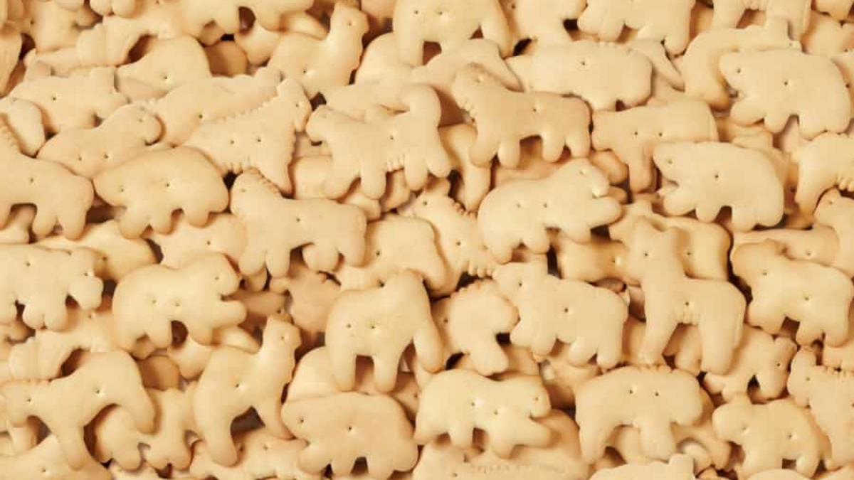 A pile of assorted animal-shaped cookies, known as animal crackers, featuring various animal designs in light golden brown color.