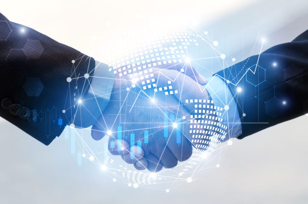 Two people in business suits shaking hands, with a digital globe and network-style graphics overlayed, symbolizing global business, partnership, and technology.