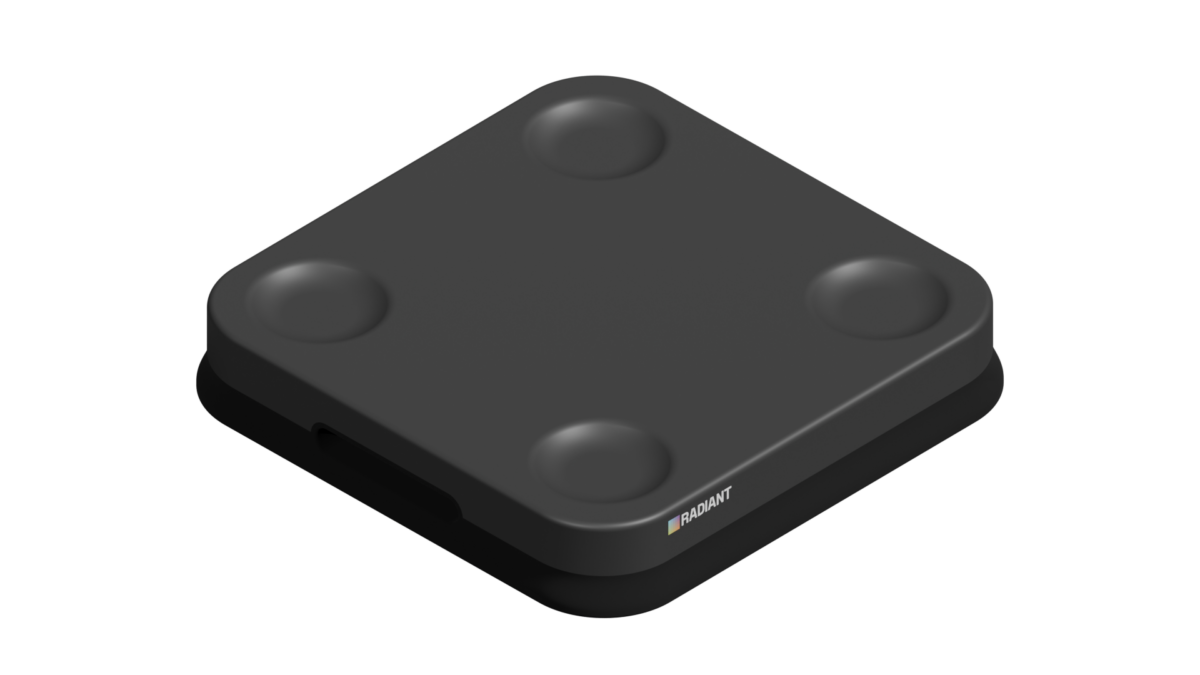 A black, square-shaped pick-to-light device with rounded corners and four circular indents on its surface, featuring a small logo and colored square near one edge, is shown against a plain white background.
