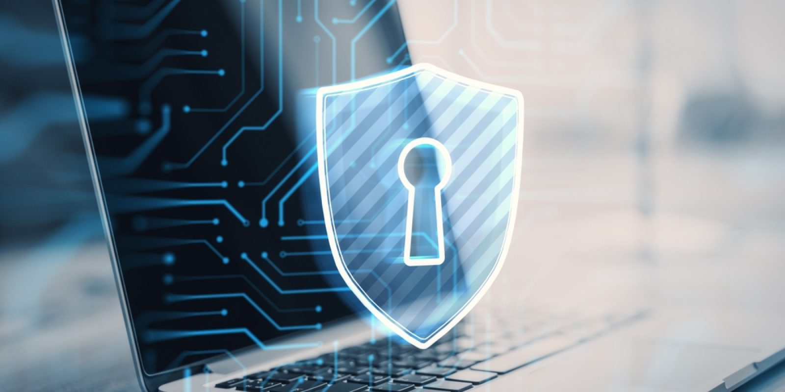 A laptop with a glowing digital shield featuring a keyhole symbol is displayed in the foreground, representing cybersecurity and online data protection for Autonomous Mobile Robots. Blue circuit lines are overlaid on the image.